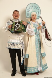 a man with an accordion and a woman with a string instrument, both wearing russian garb