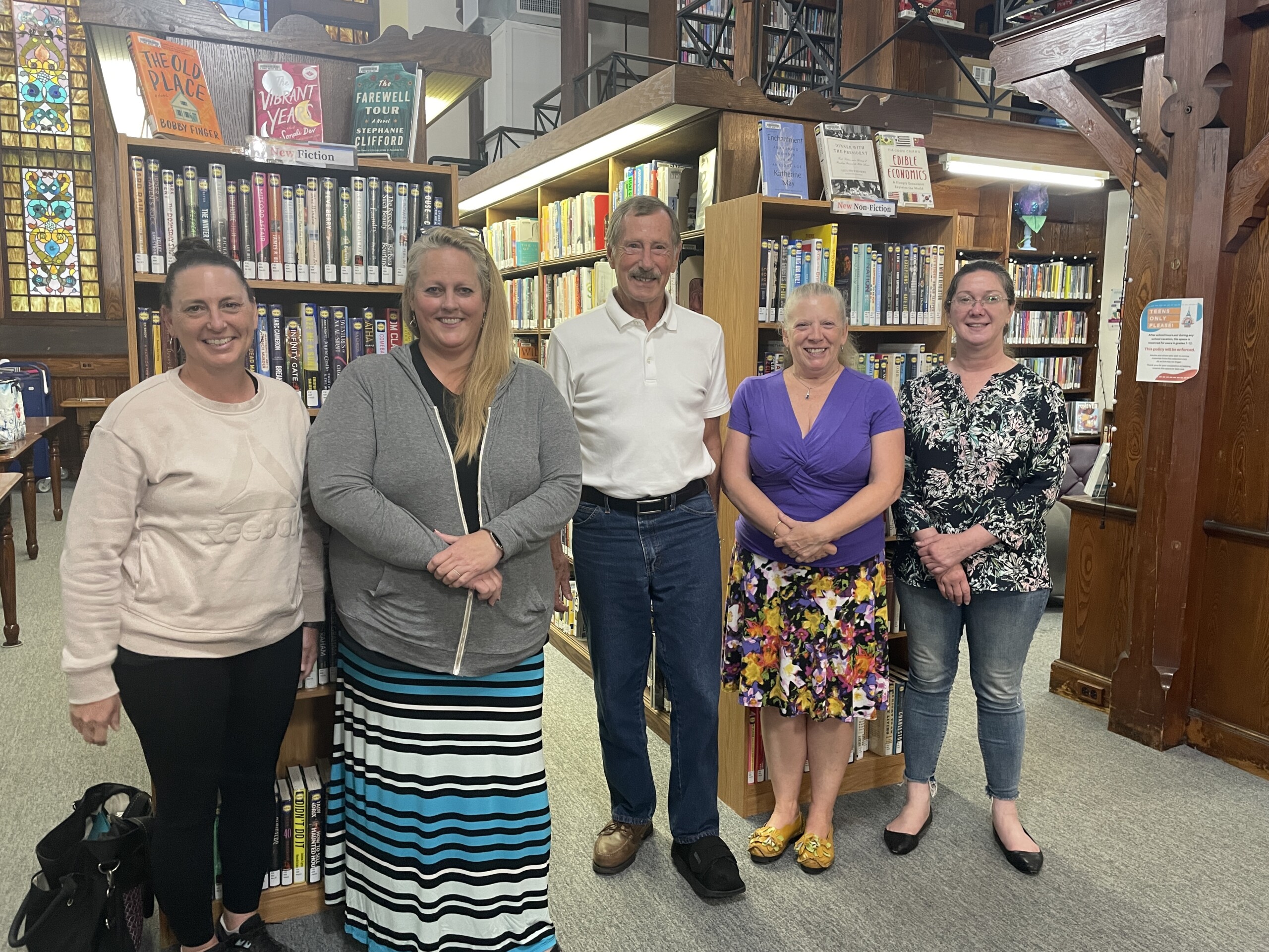 Board of Trustees, photo of four women and one man smiling at the camera in front of book cases.