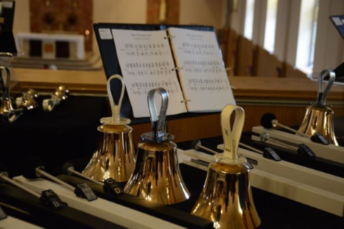 [image] three hand bells standing in front of sheet music