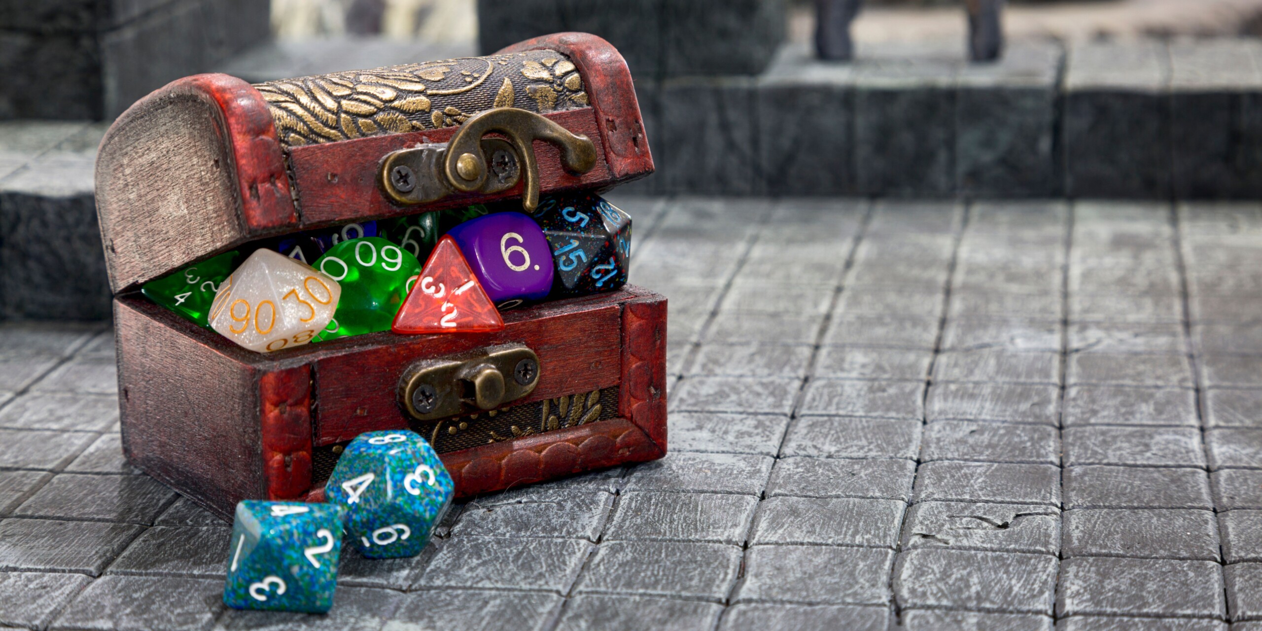 image: small chest with polyhedral dice on a grey castle terrain.